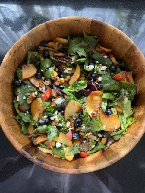 Overhead view of peach and blueberry salad with feta, mixed leaves and walnuts