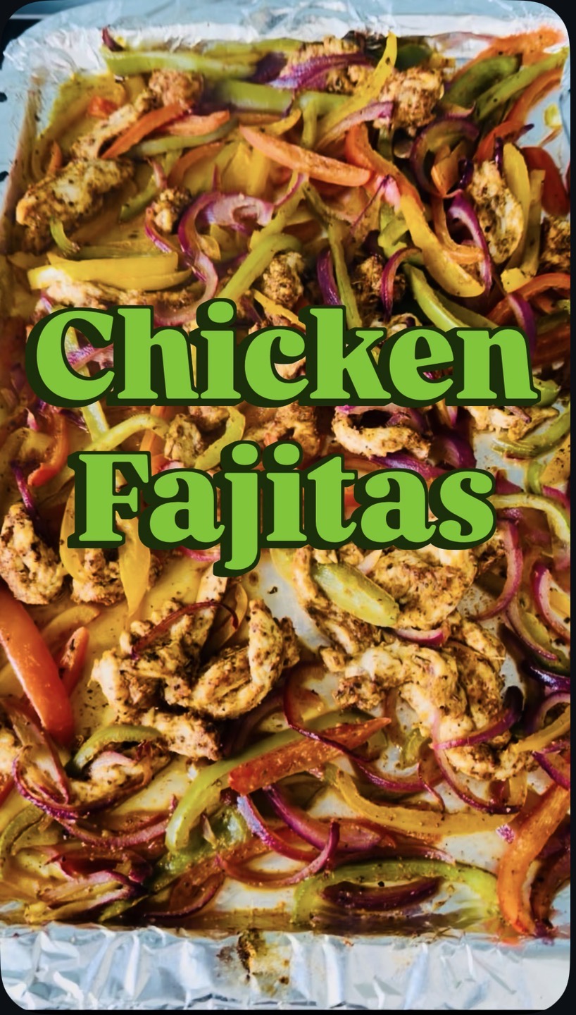 Baked sheet pan chicken fajitas with capsicums and red onion on a foil-lined tray