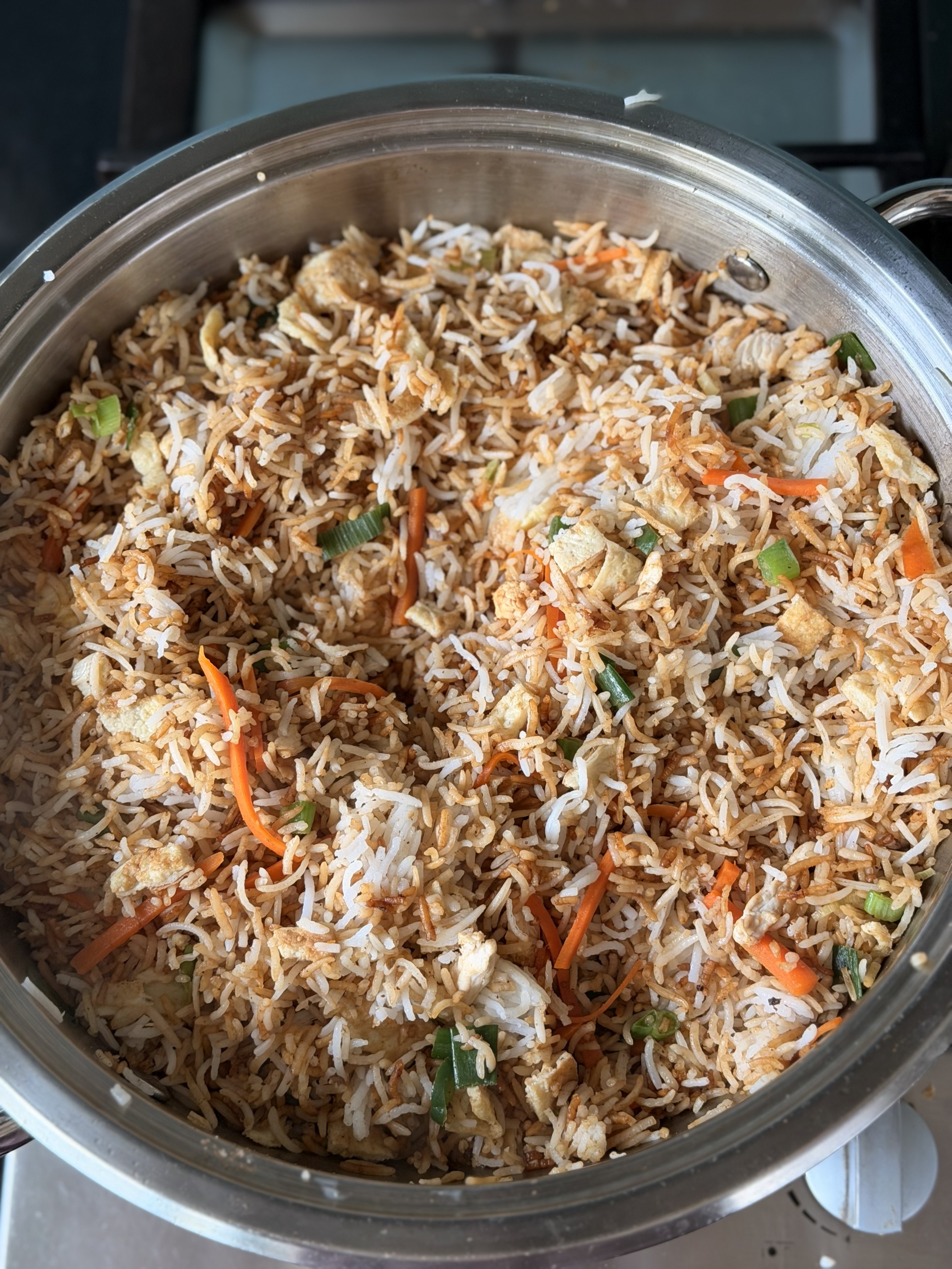 A pan of chicken masala rice with chicken, omelette pieces, carrot and green onion