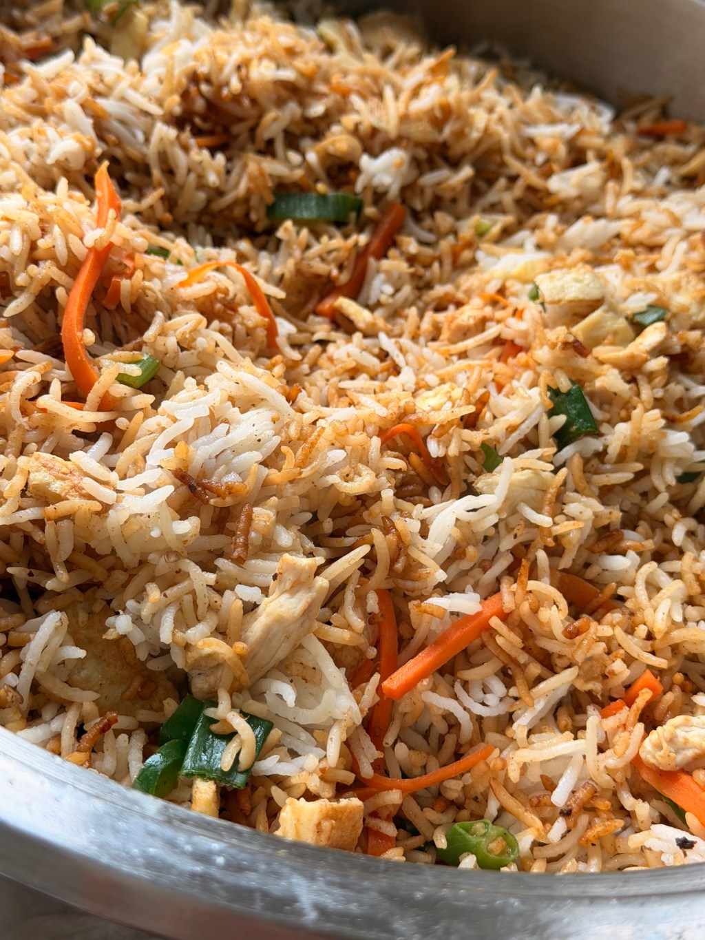 Close-up of chicken masala rice with carrot strips, green onion and pieces of omelette