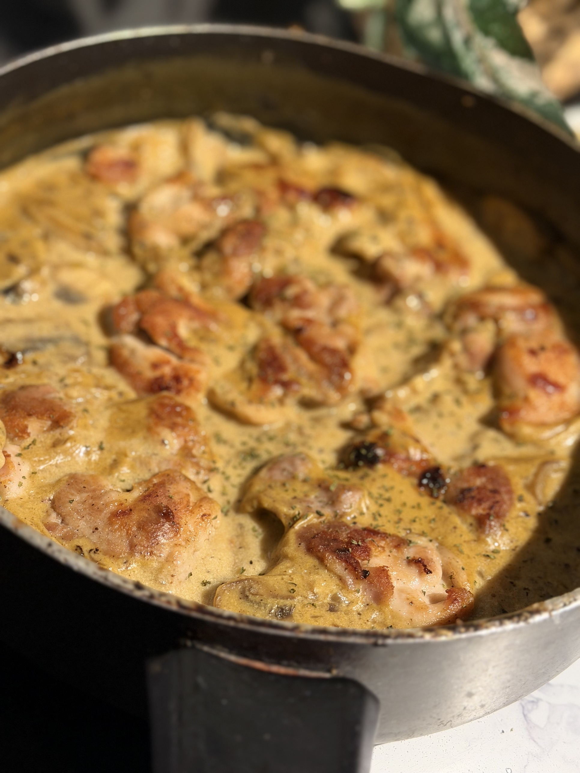 Close-up of golden chicken thighs in creamy mushroom sauce