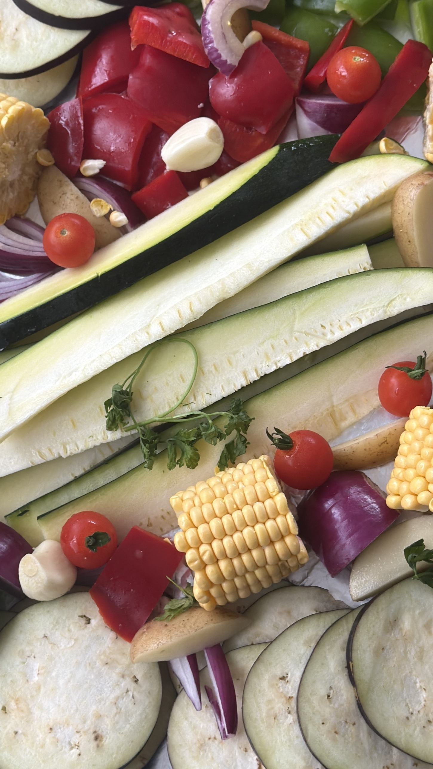 Fresh aubergine, courgette, corn, peppers, onion, potatoes and tomatoes cut and ready