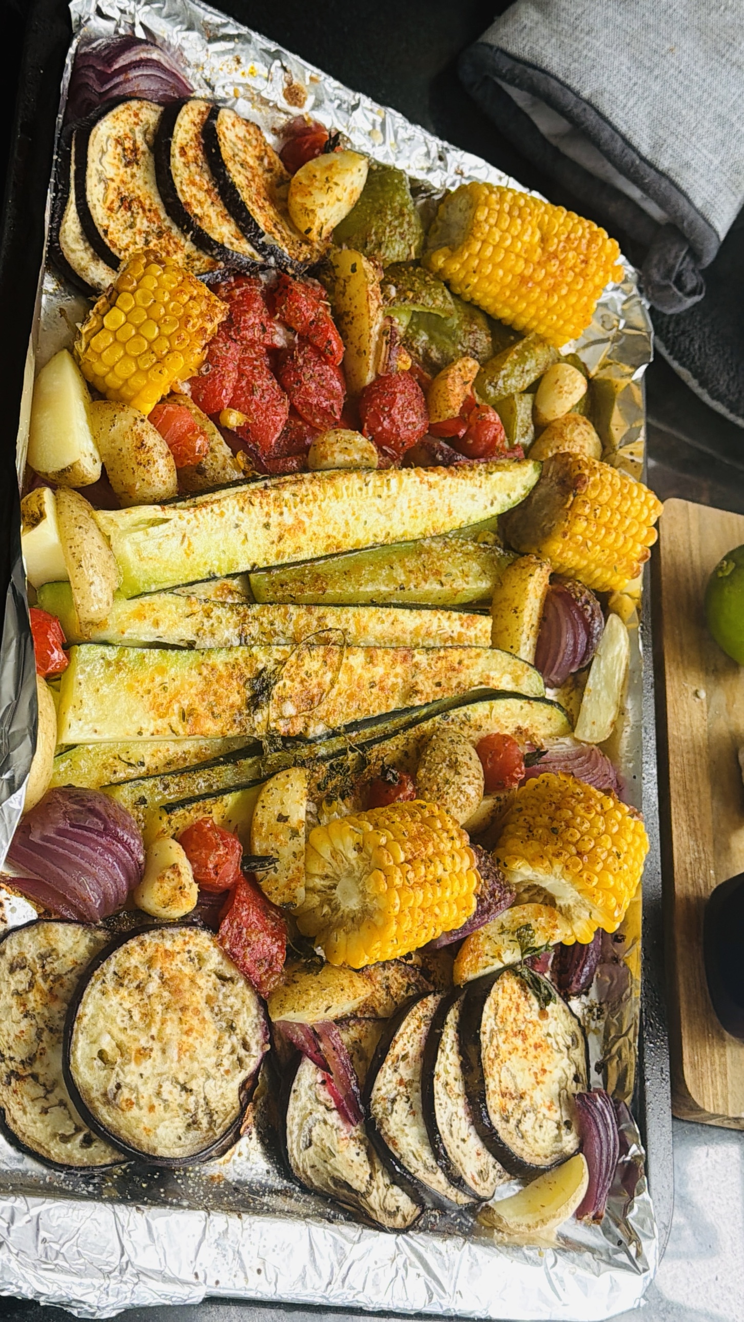 A tray of roasted aubergine, courgette, corn, peppers, potatoes and tomatoes